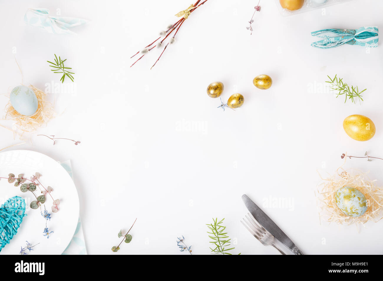 Easter table setting with gold and blue eggs and cutlery on white. Holidays background. Backdrop with copy space, flat lay, top view. Stock Photo