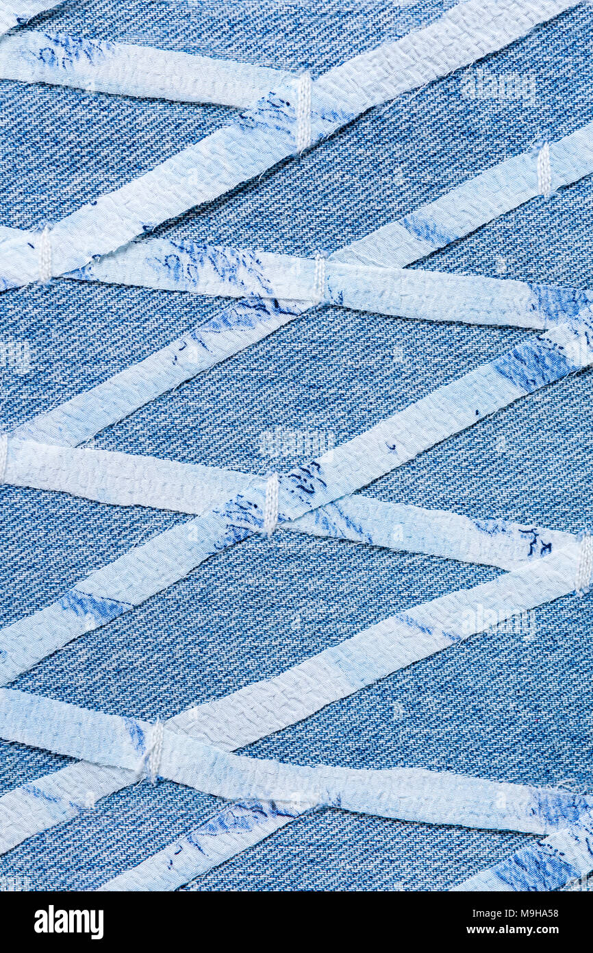 Thin stripes cutted from fine cloth, sewn on blue denim in geometric rhomboid pattern. Stock Photo