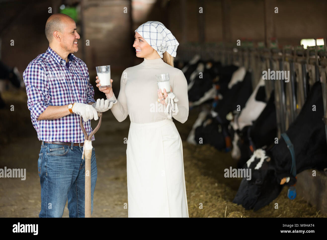 Portrait of two happy smiling farmers holding glass with fresh milk in ...