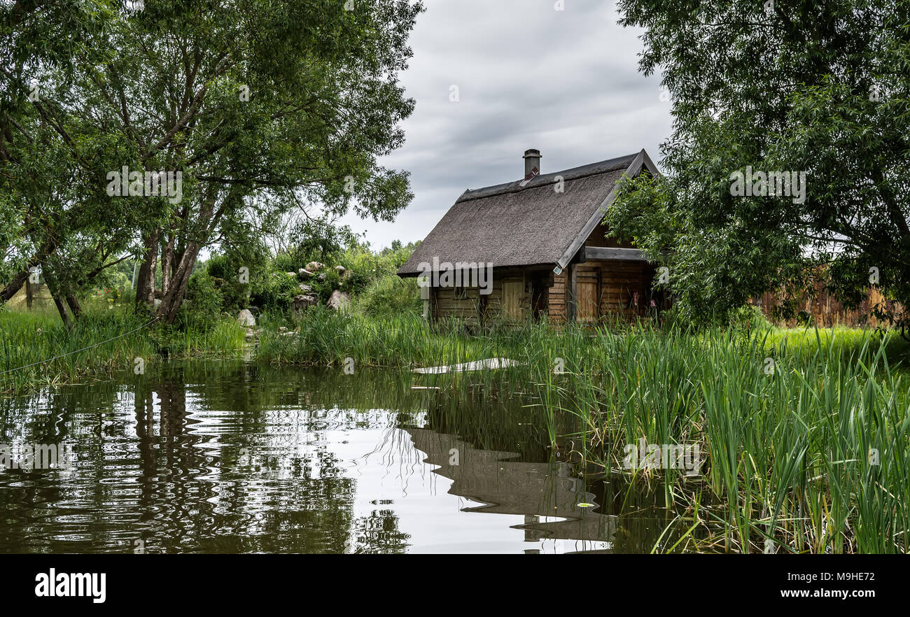 Amazing View On Lonely Cabin Near The Lake Among Trees Stock Photo
