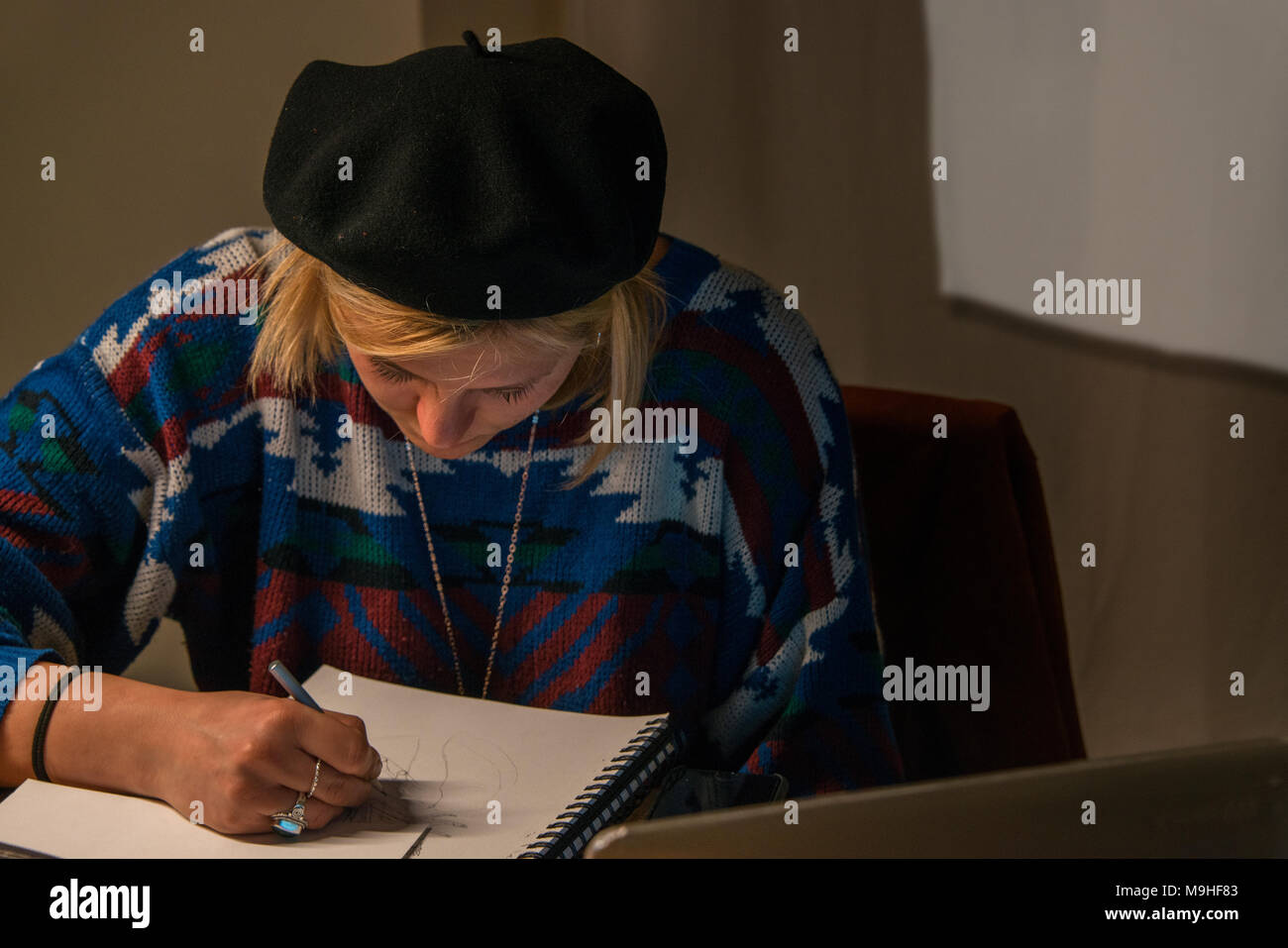 Woman wearing a beret, sketching on an art pad. Stock Photo