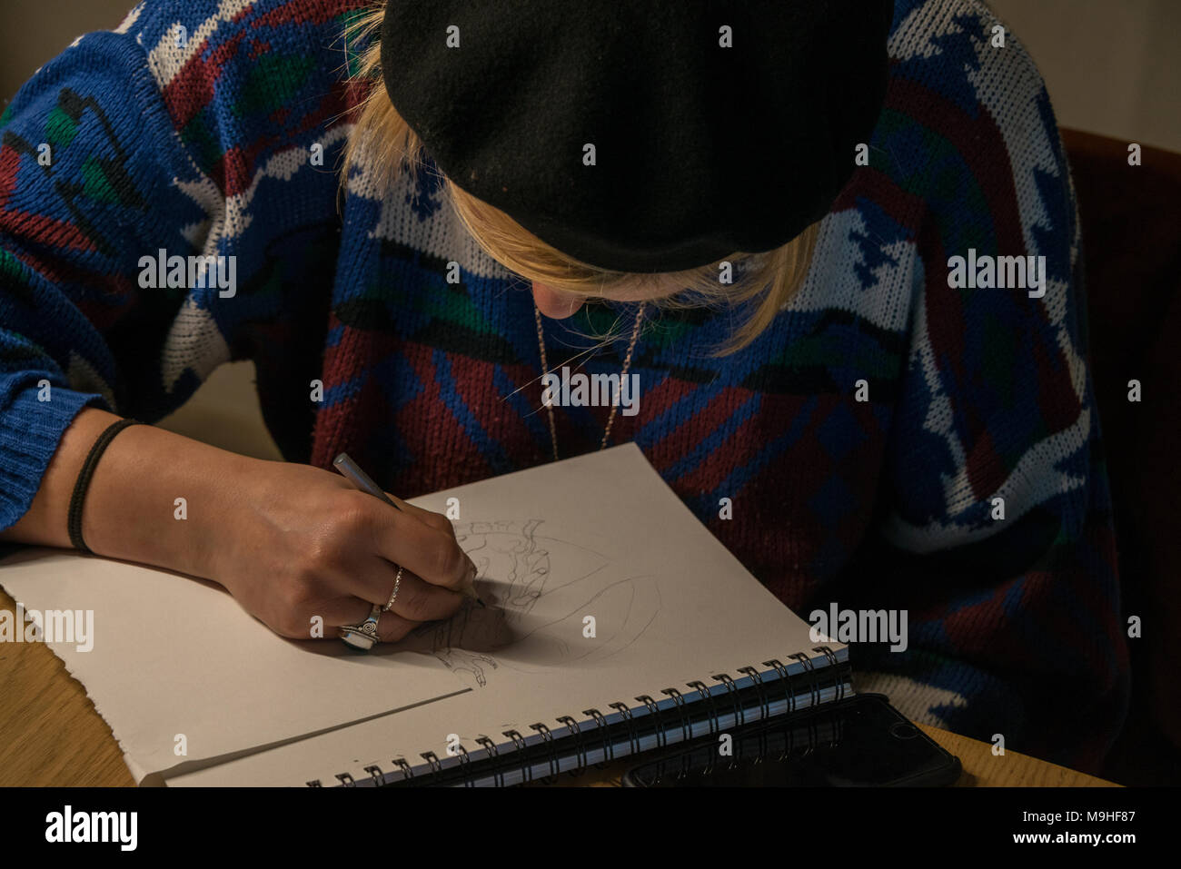 Woman wearing a beret, sketching on an art pad. Stock Photo