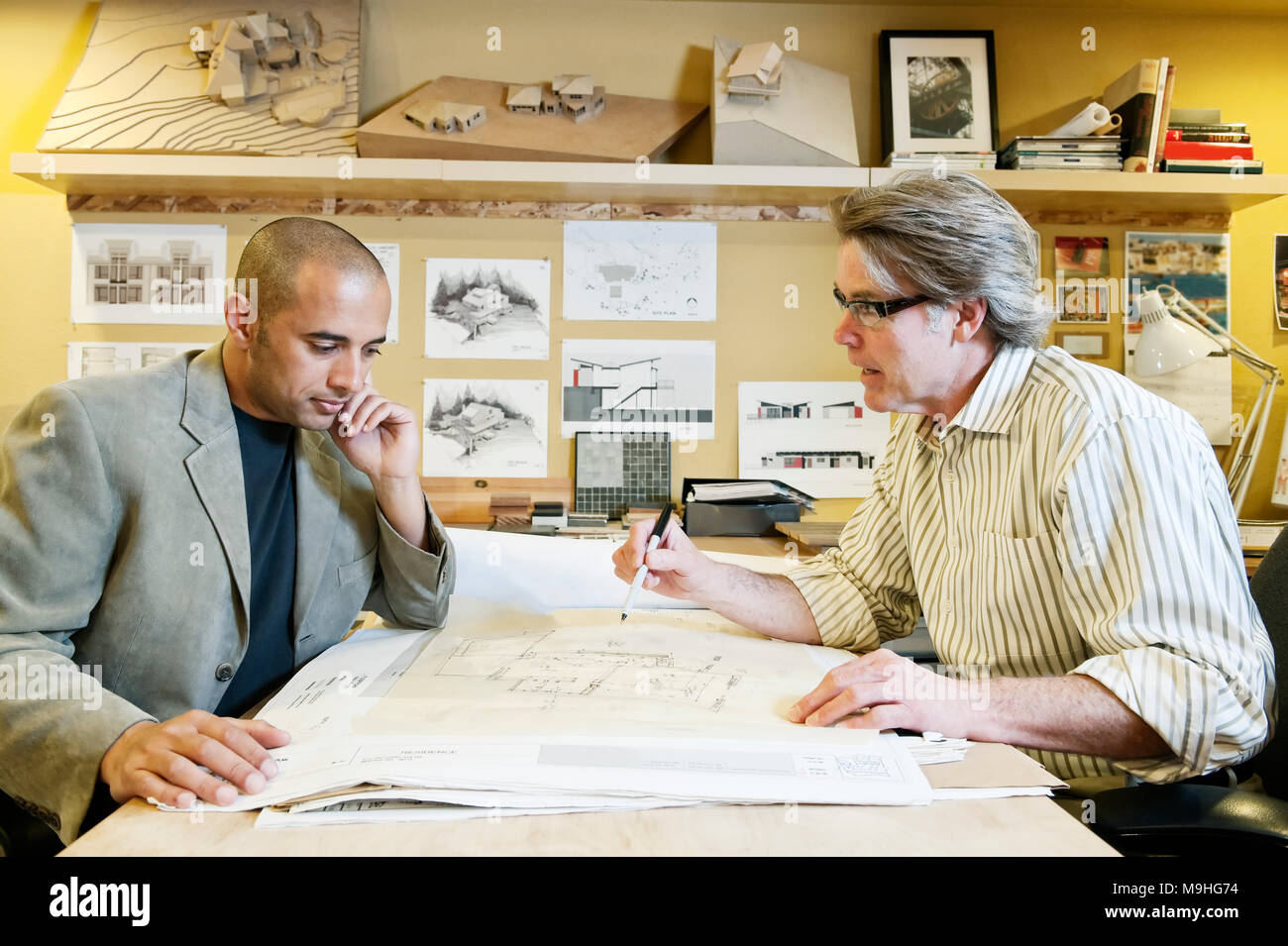 A multi-ethnic team of two male architects working on plans for a new home in an architect's office. Stock Photo
