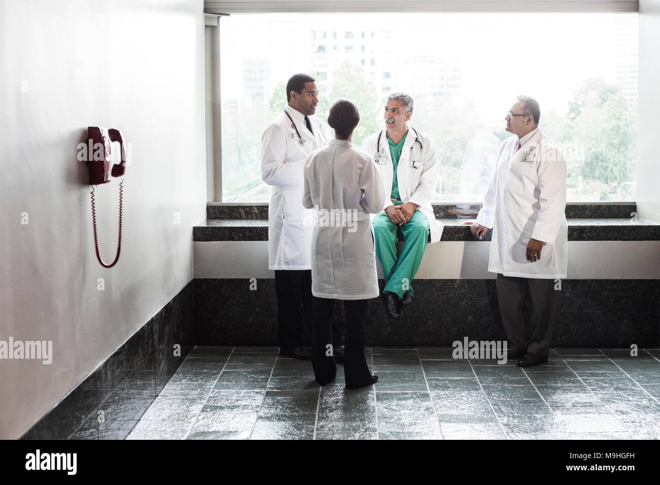 Mixed race doctors conferring iin a hospital hallway. Stock Photo