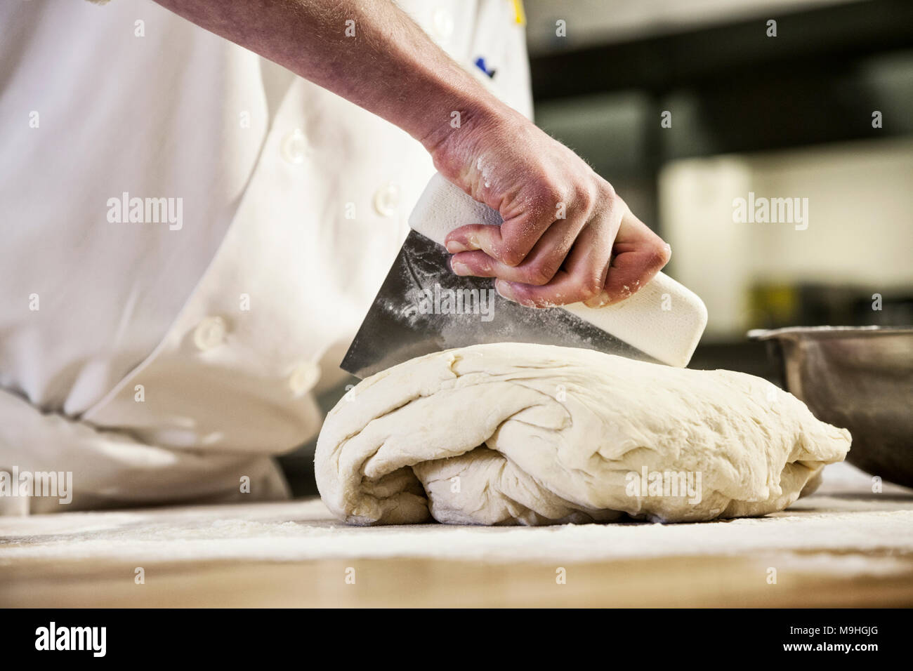 A chef dividing up bread dough into sections on a floured worktop. Stock Photo