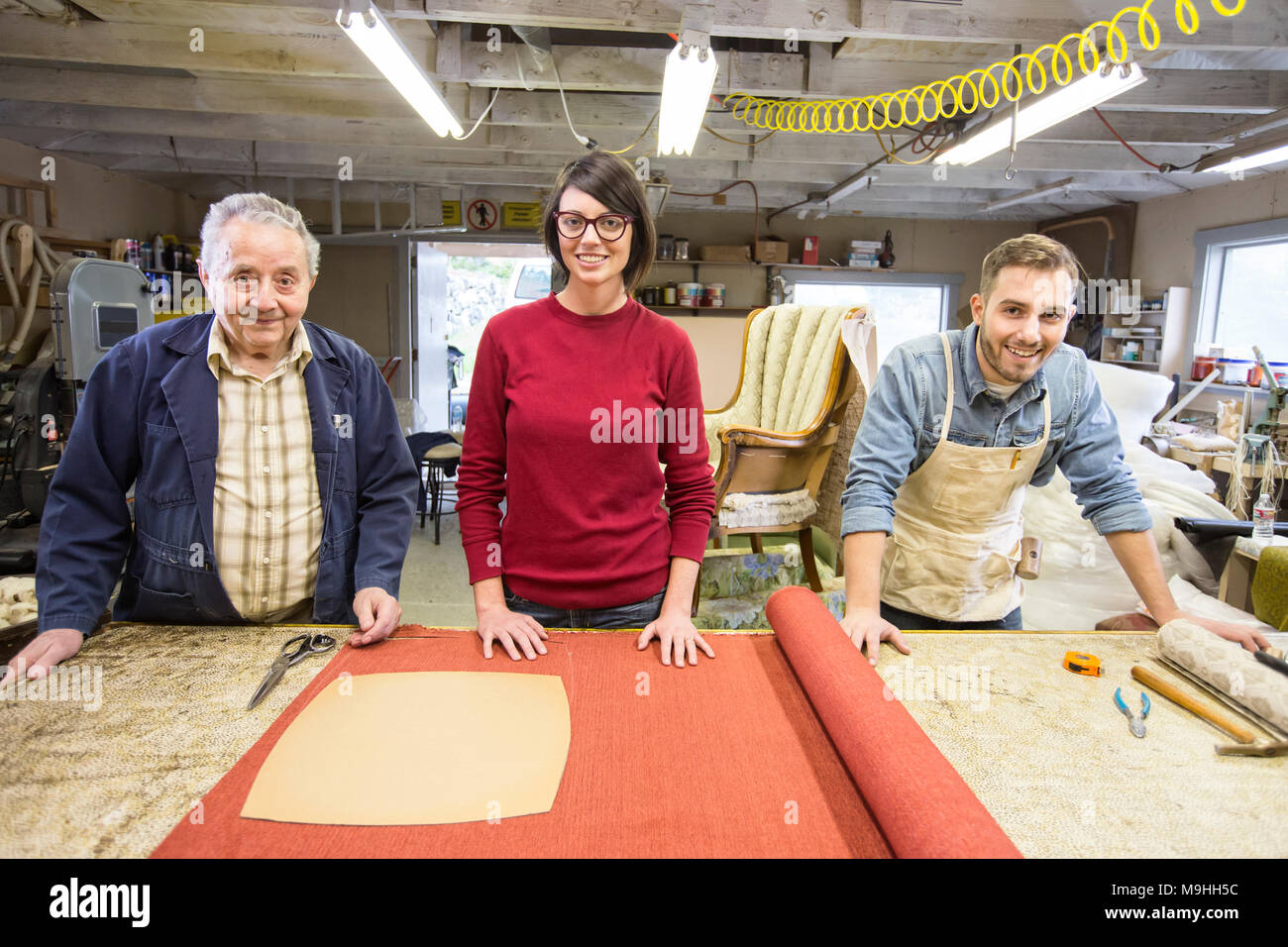 Senior Caucasian man upholsterer and his understudy team of young ...