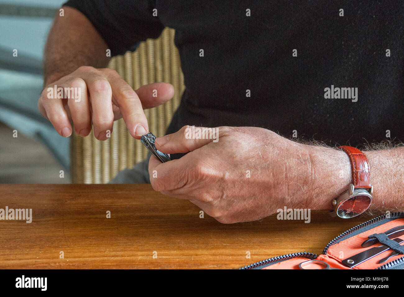 Man cutting fingernails with a nail clipper Stock Photo