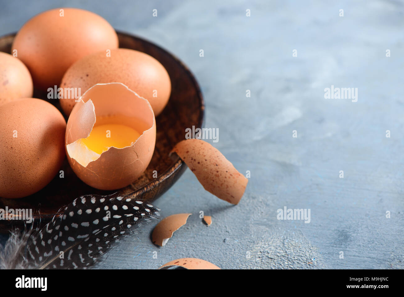 Yolk in an eggshell close-up. Raw cooking ingredients background with copy space. Modern Easter concept with brown hen eggs Stock Photo