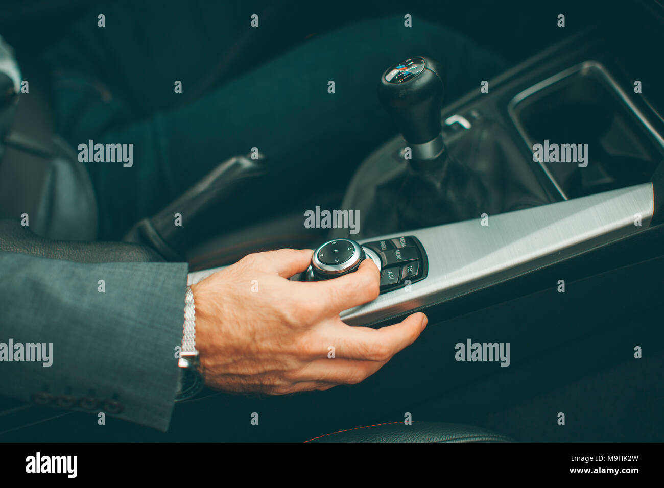 View at young handsome man changing gears during driving of modern car