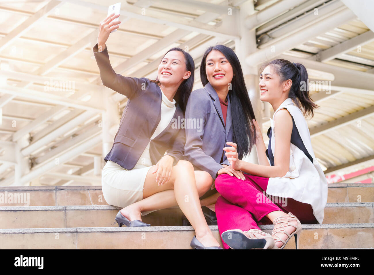 Businesswoman sitting and using smartphone to take selfie with colleague together Stock Photo