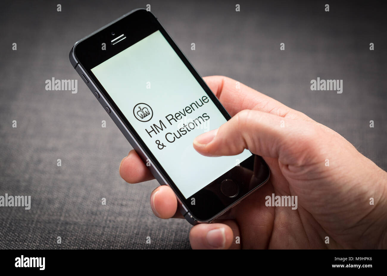 A man using the HMRC HM Revenue and Customs app on an iPhone in the UK Stock Photo