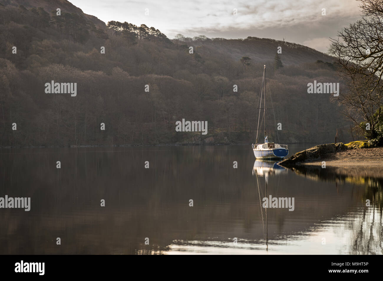 A lone yaught moored by the shore on Coniston Water in the Lake District. Stock Photo