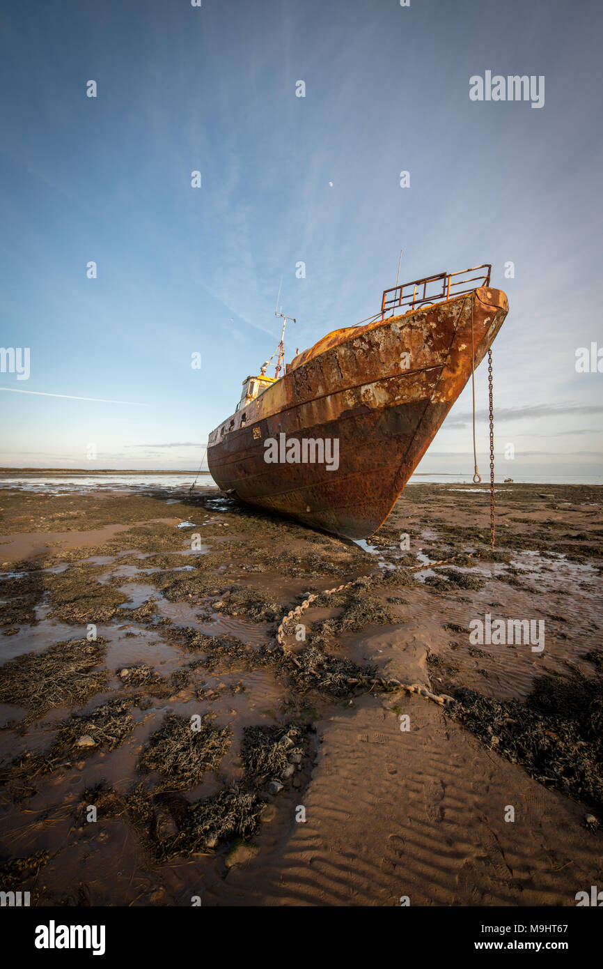 An old beached trawler slowly rusting on the beach at Rampside near Barrow-in-Furness, Cumbria. Stock Photo