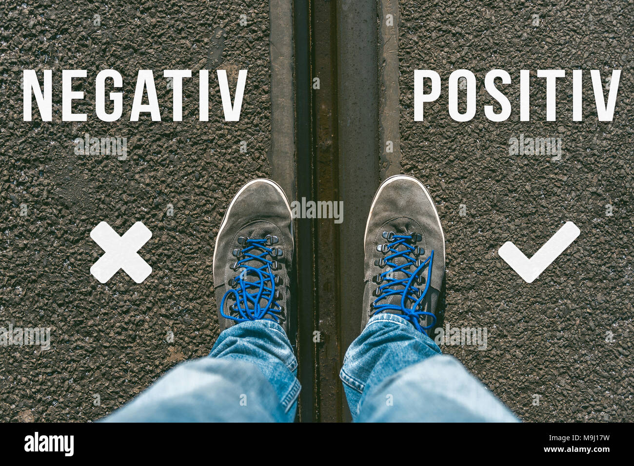 Reaching a crossroads having to decide between negativ and positiv in german meaning negative and positive symbolized by two feet and shoes standing o Stock Photo
