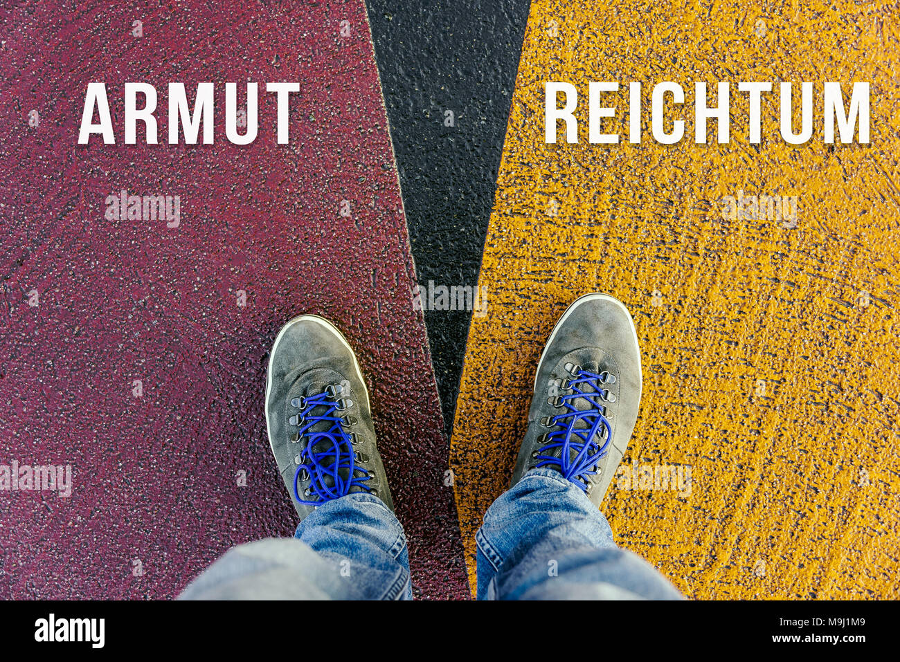 Reaching a crossroads having to choose between armut and reichtum in german meaning poverty and wealth symbolized by two feet standing on two differen Stock Photo