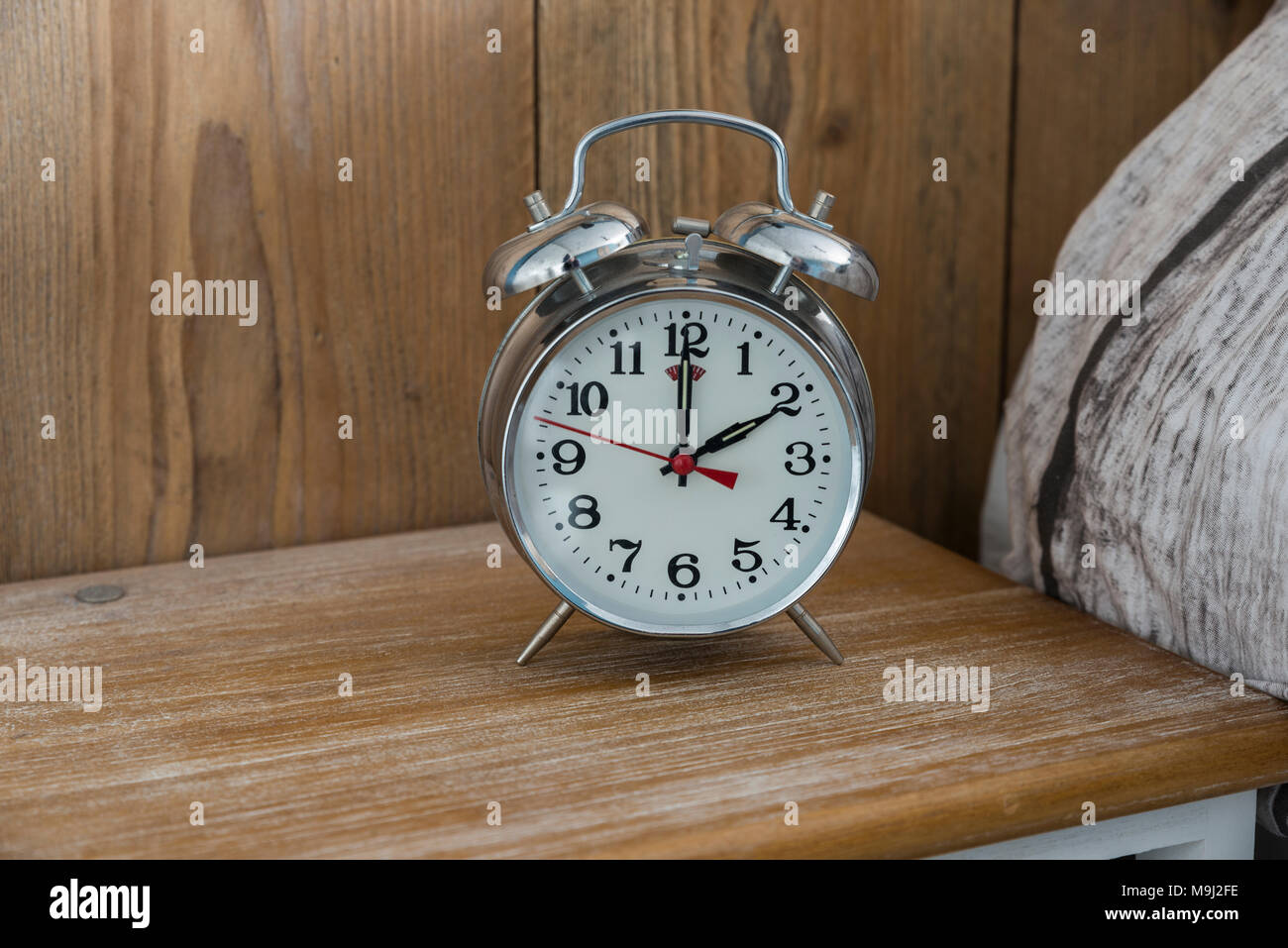 An old fashioned silver coloured bed side analogue pre digital alarm clock Stock Photo