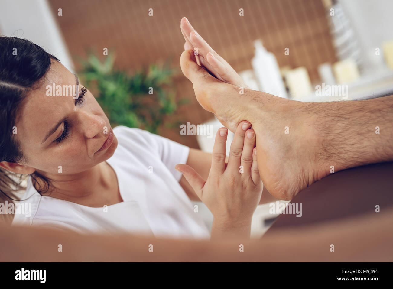 Close-up of a young female therapist massaging young man's foot at beauty salon. Stock Photo