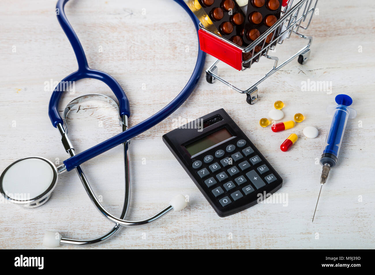 Shopping trolley with pills,money and calculator on a wooden background.  Paid medicine. Purchase of medicines Stock Photo - Alamy
