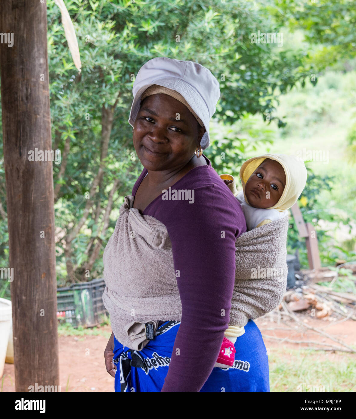 african woman with baby in a sling, in africa it is normal for woman to carrie their baby in a sling, to work or when shoppingg Stock Photo