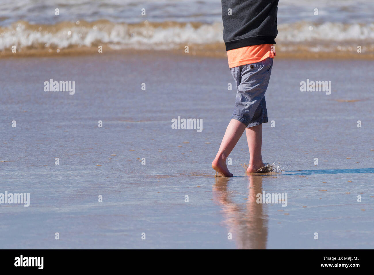 A young child paddling in the sea at Fistral Beach in Newquay Cornwall. Stock Photo