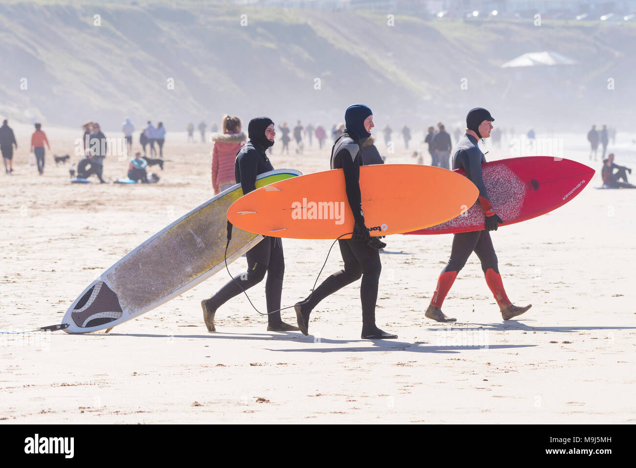 UK surfing - surfers carrying their surboards across Fistral beach in Newquay Cornwall. Stock Photo