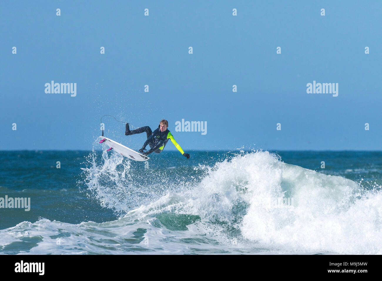 A surfer performing a spectacular jump from the top of a wave at Fistral in Newquay Cornwall. Stock Photo