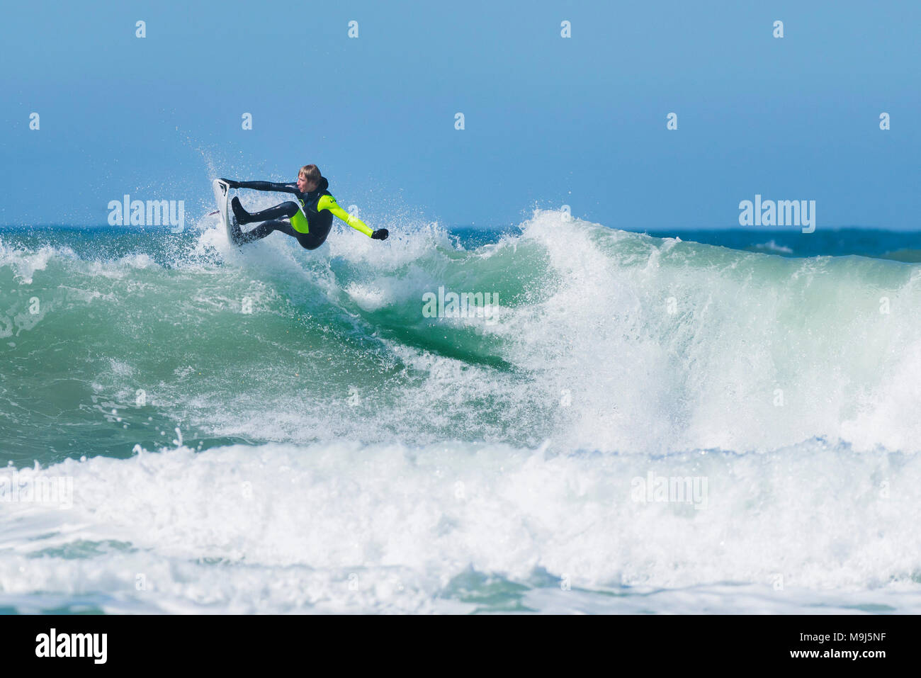 A surfer performing a spectacular trick at the top of a wave at Fistral in Newquay Cornwall. Stock Photo