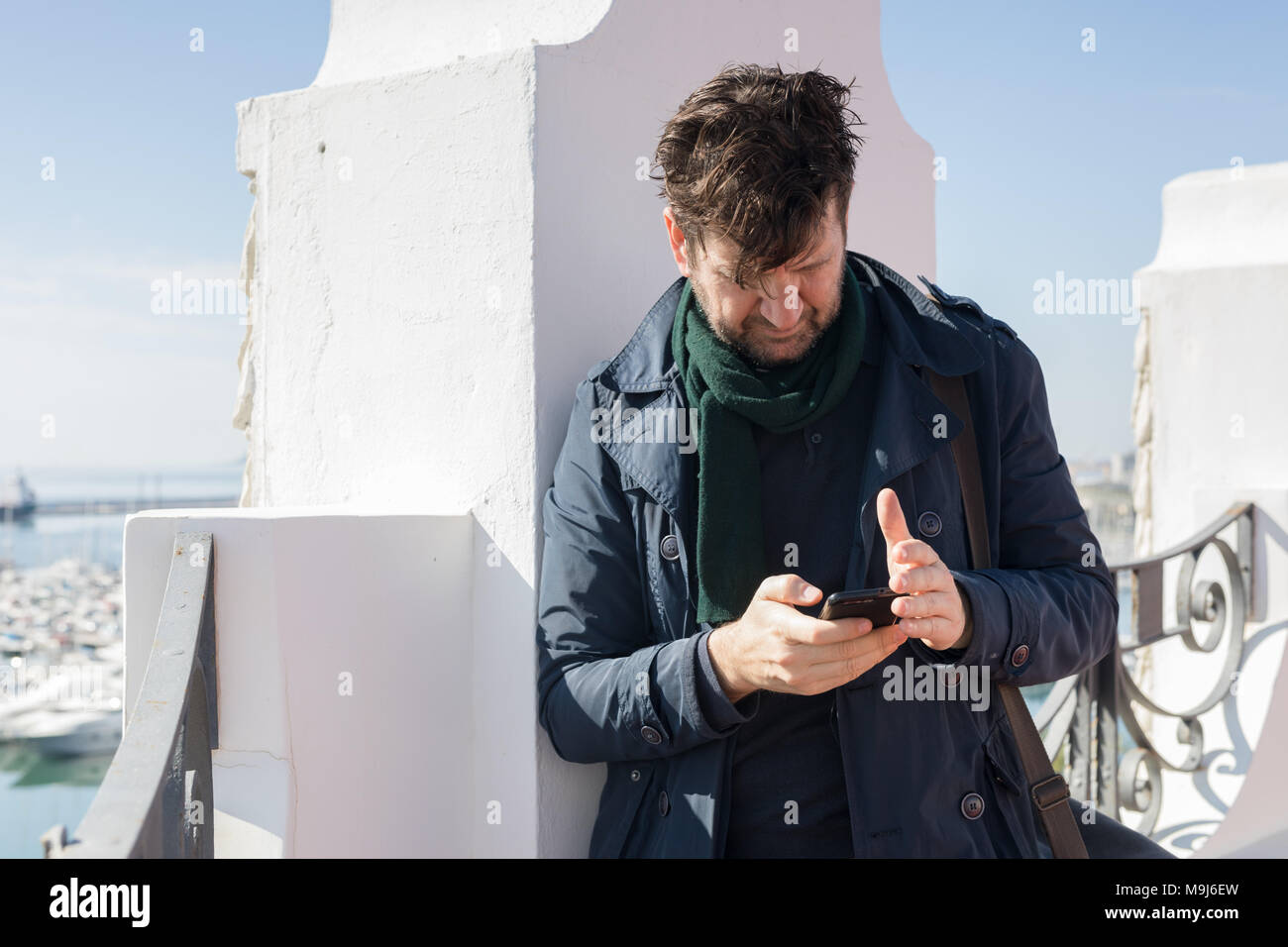 portrait of 45 year old man with blue jacket and mobile in his hand Stock Photo