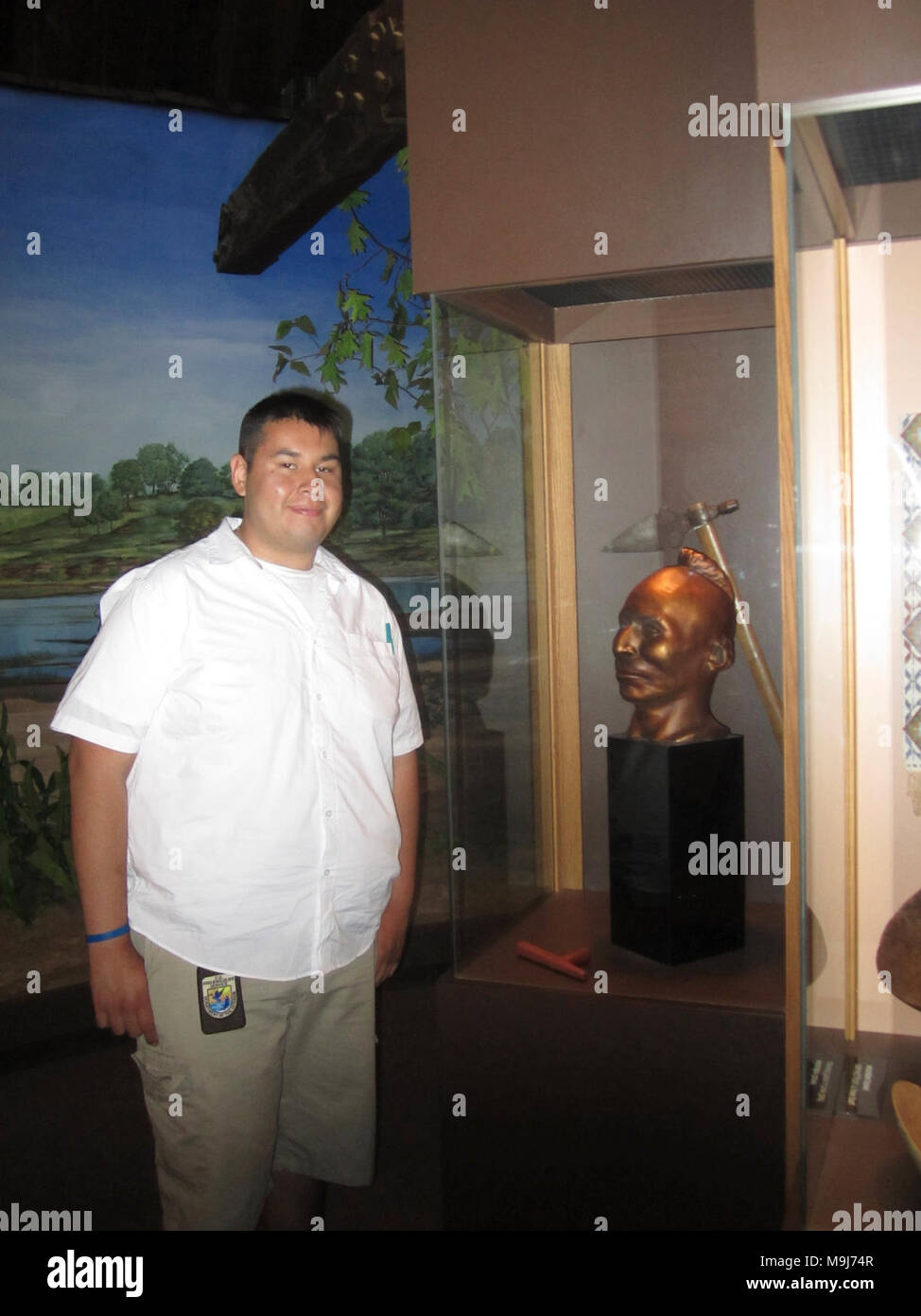 Alejandro Morales, SCEP student intern, poses for a picture with a Black Hawk sculpture at the Hauberg Indian Museum. Stock Photo