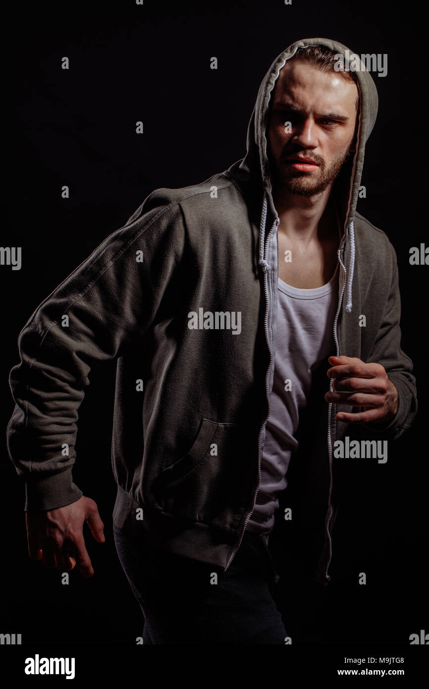 rapper in hoodie is running away from rockers. escape the police. running away from dog Stock Photo