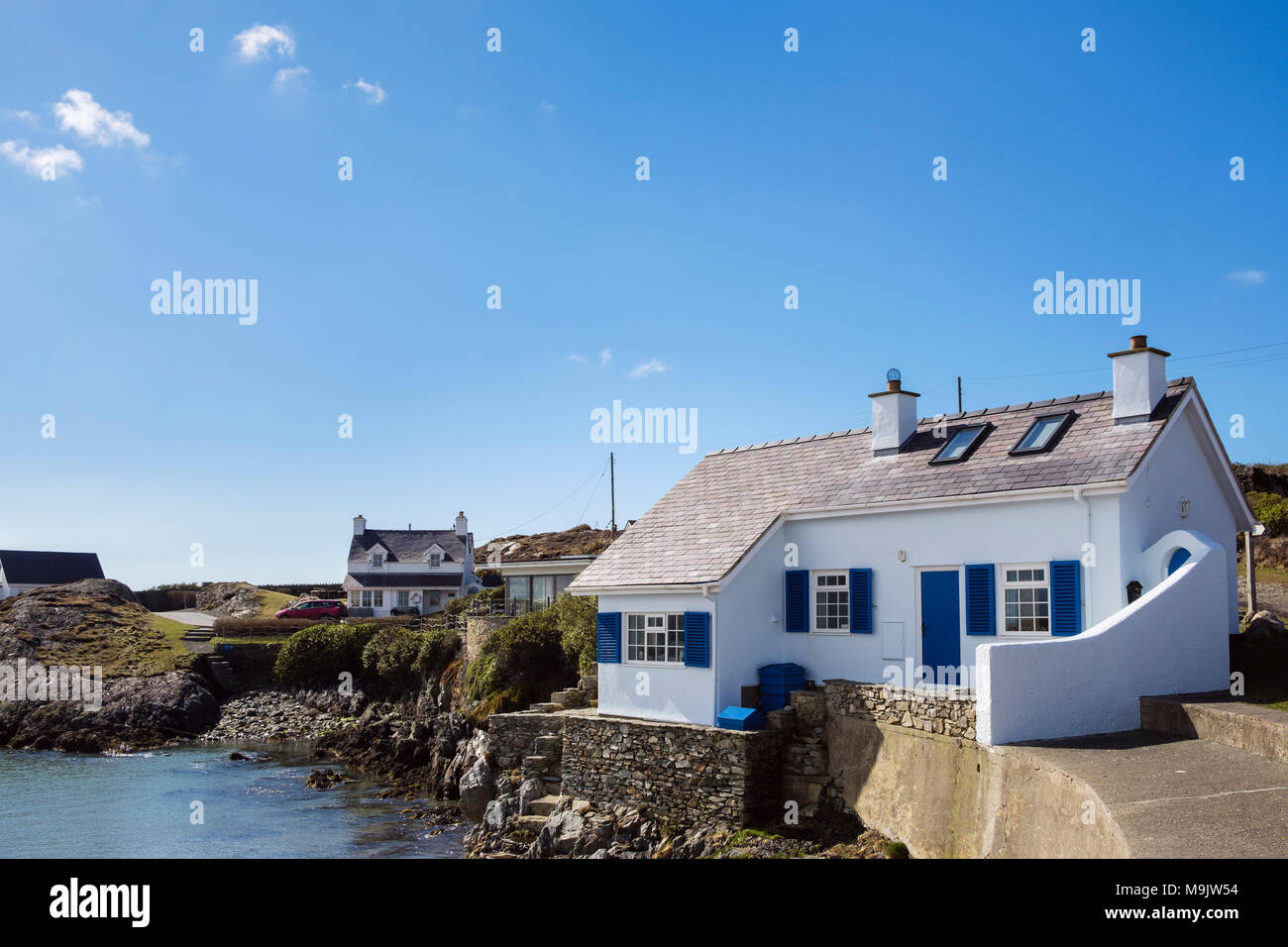 Quaint traditional old Welsh white cottage overlooking a rocky cove in small village. Rhoscolyn Holy Island Isle of Anglesey Wales UK Britain Stock Photo