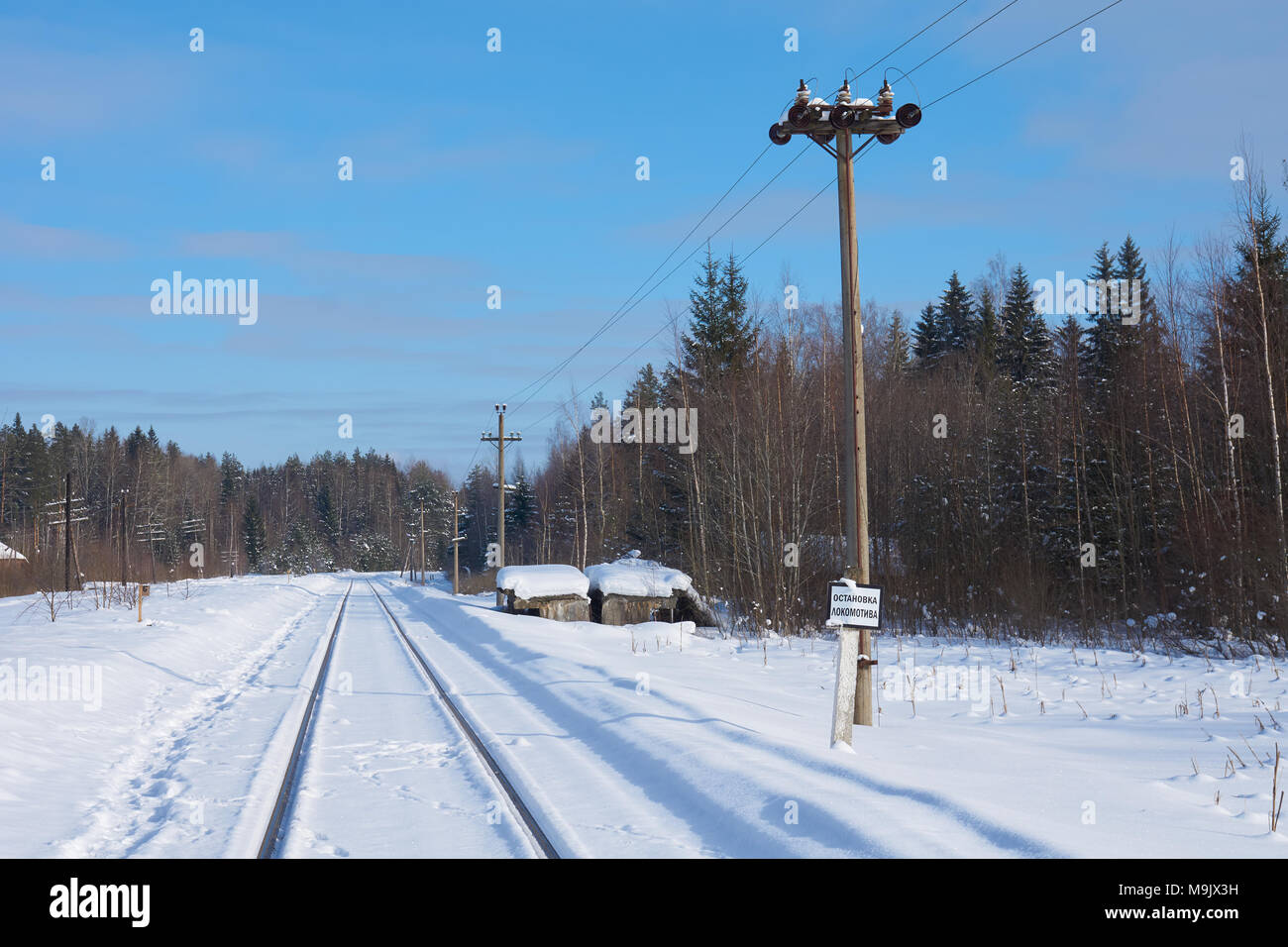 Railway whistle stop in Zhukopa in winter, Peno district, Tver oblast, Russia. Russian text on railway sign on the right: locomotive stop. Stock Photo