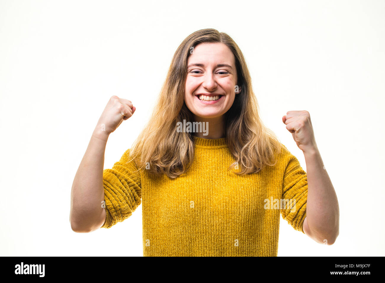 Celebrating success - A happy smiling positive enthusiastic  young Caucasian woman girl , pumping her fists in exuberance, full of passion and committment  - UK Stock Photo
