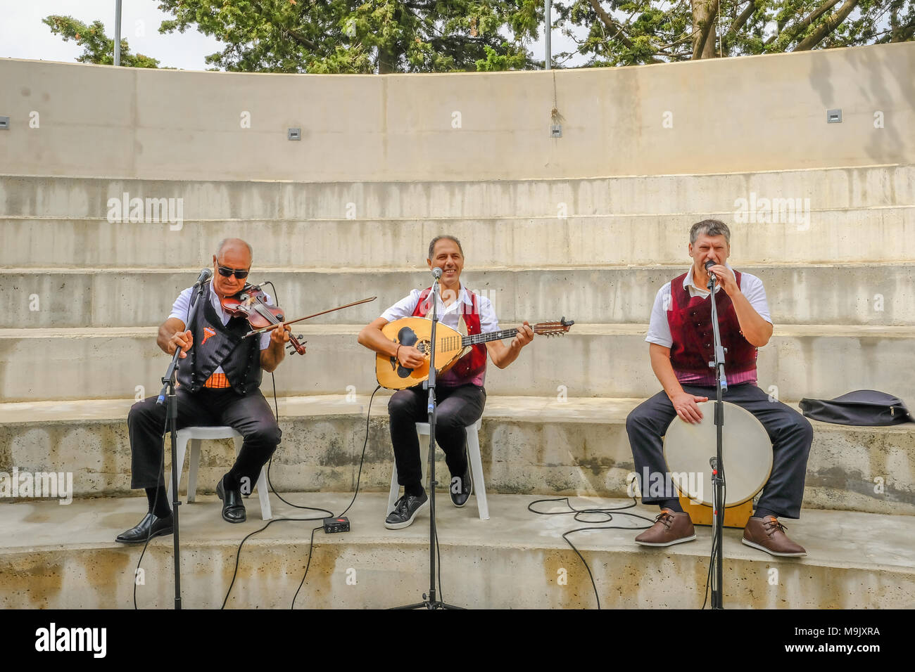 Arsos, Cyprus - October 8, 2017:  Cypriot trio of musicians playing drum, violin and laouto. Stock Photo