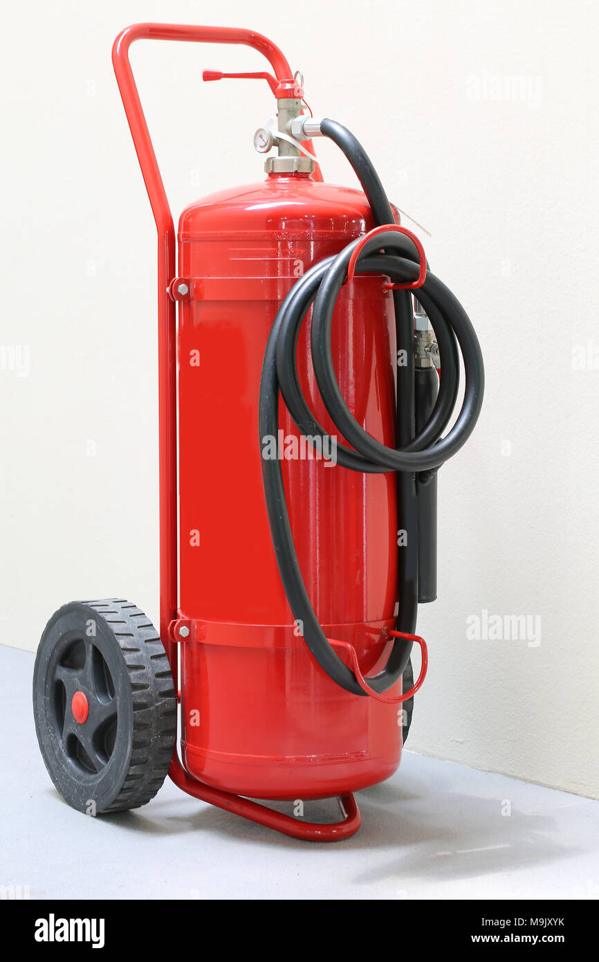 Big red wheeled fire extinguisher with black pipe Stock Photo