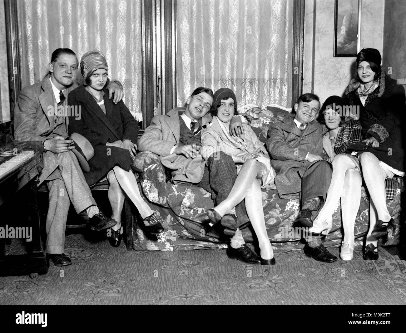 Flappers and their dates frolic on the couch, ca. 1924. Stock Photo