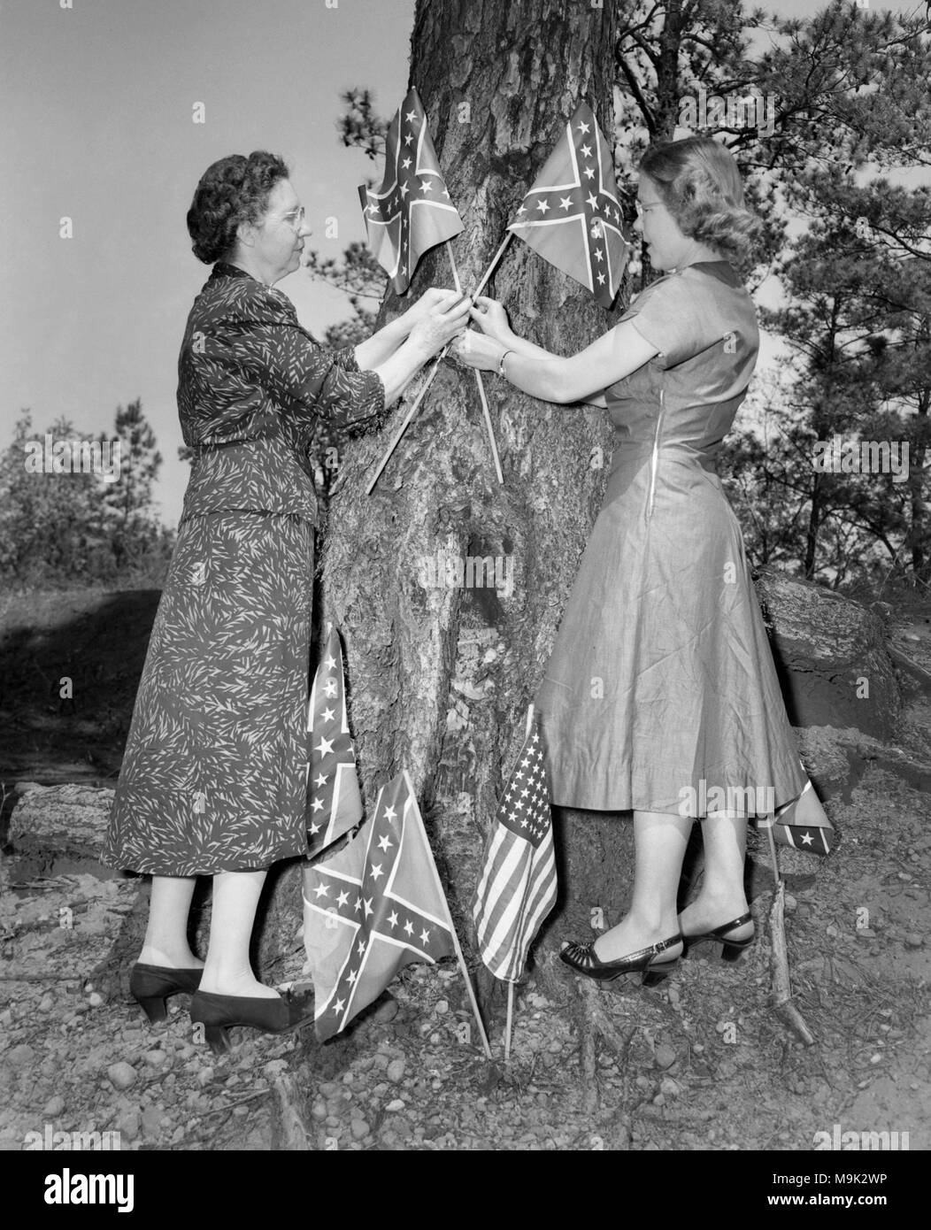 Two women decorate a tree with Confederate flags for a Confederate Memorial Day service in Georgia, ca. 1952. Stock Photo