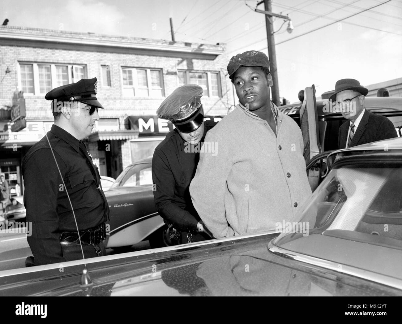 Police in California handcuff a bank robbery suspect on the street, ca. 1961. Stock Photo