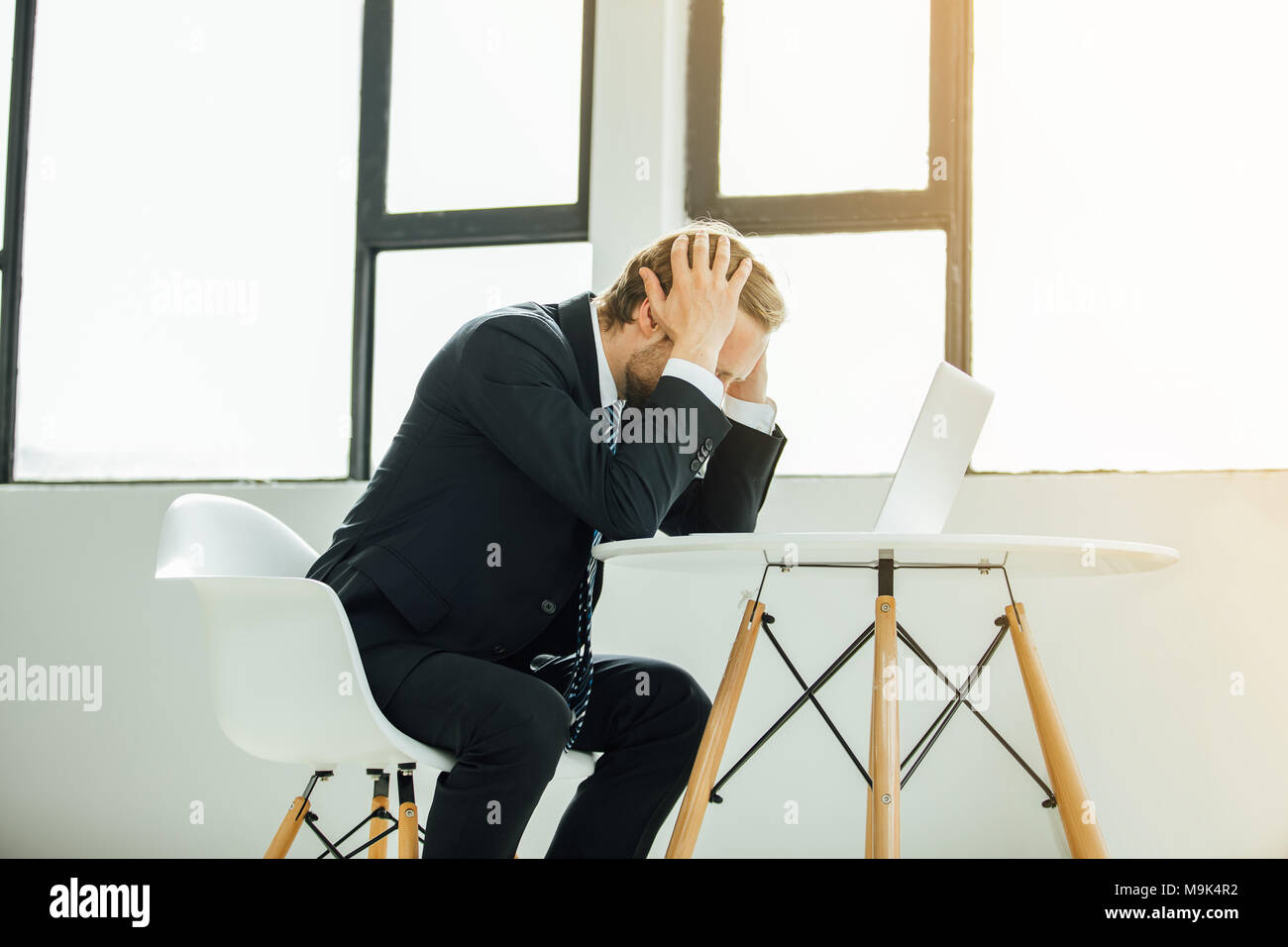 man in costume, sales manager or stockbroker, looking at the laptop screen with horror, extremely upset, seeing the disaster Stock Photo