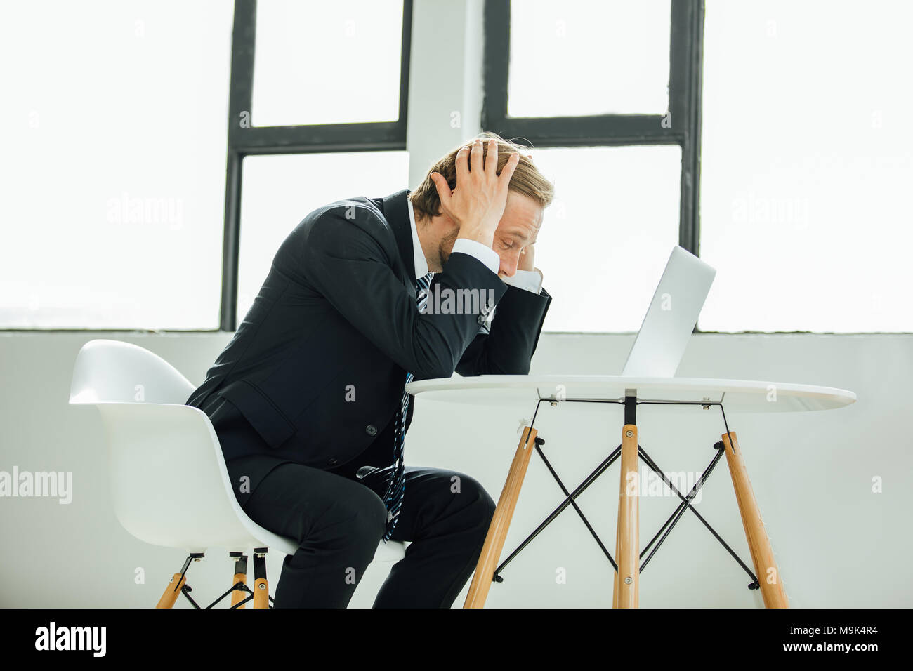 man in costume, sales manager or stockbroker, looking at the laptop screen with horror, extremely upset, seeing the disaster Stock Photo