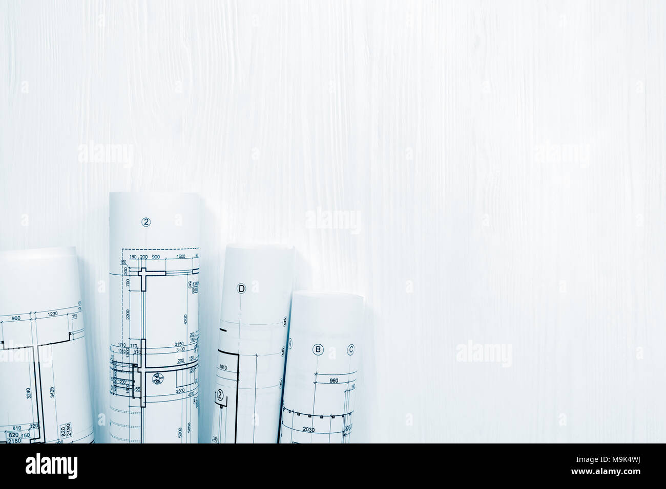 rolls of architectural drawings and blueprints on white wooden ...