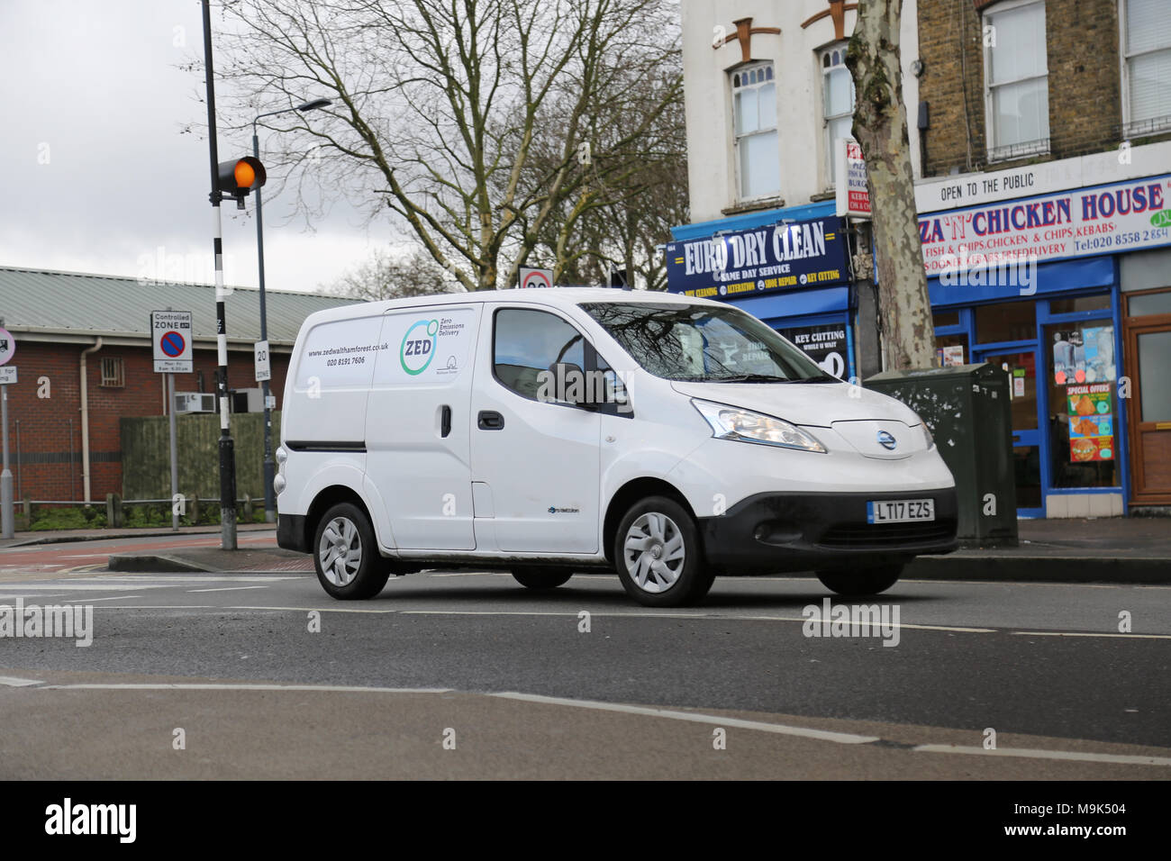 A white Nissan e-NV200 electric van makes deliveries in North London, UK. Branded: Zero Emissions Deliveries' Stock Photo