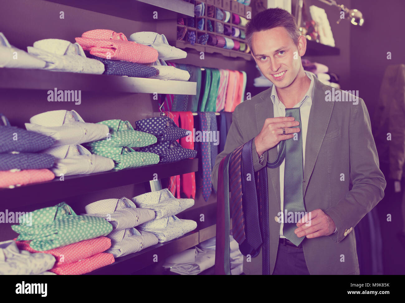 Glad man choosing new tie in male cloths store Stock Photo - Alamy