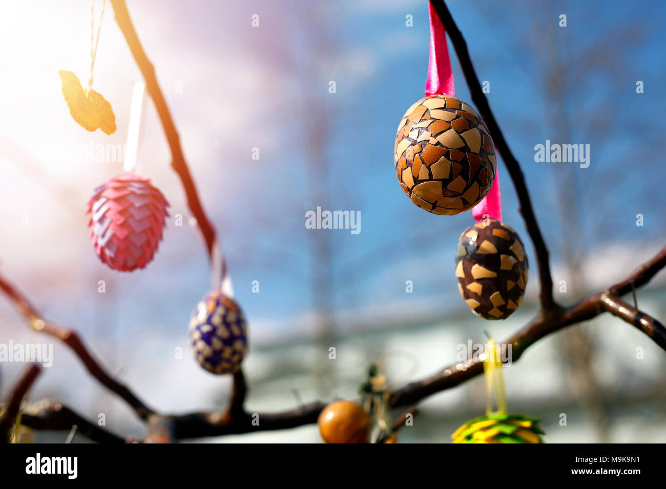 Painted Easter eggs covered with colorful pieces of eggshell. Decorated eggs hanging on the tree. Creative and innovative. Stock Photo