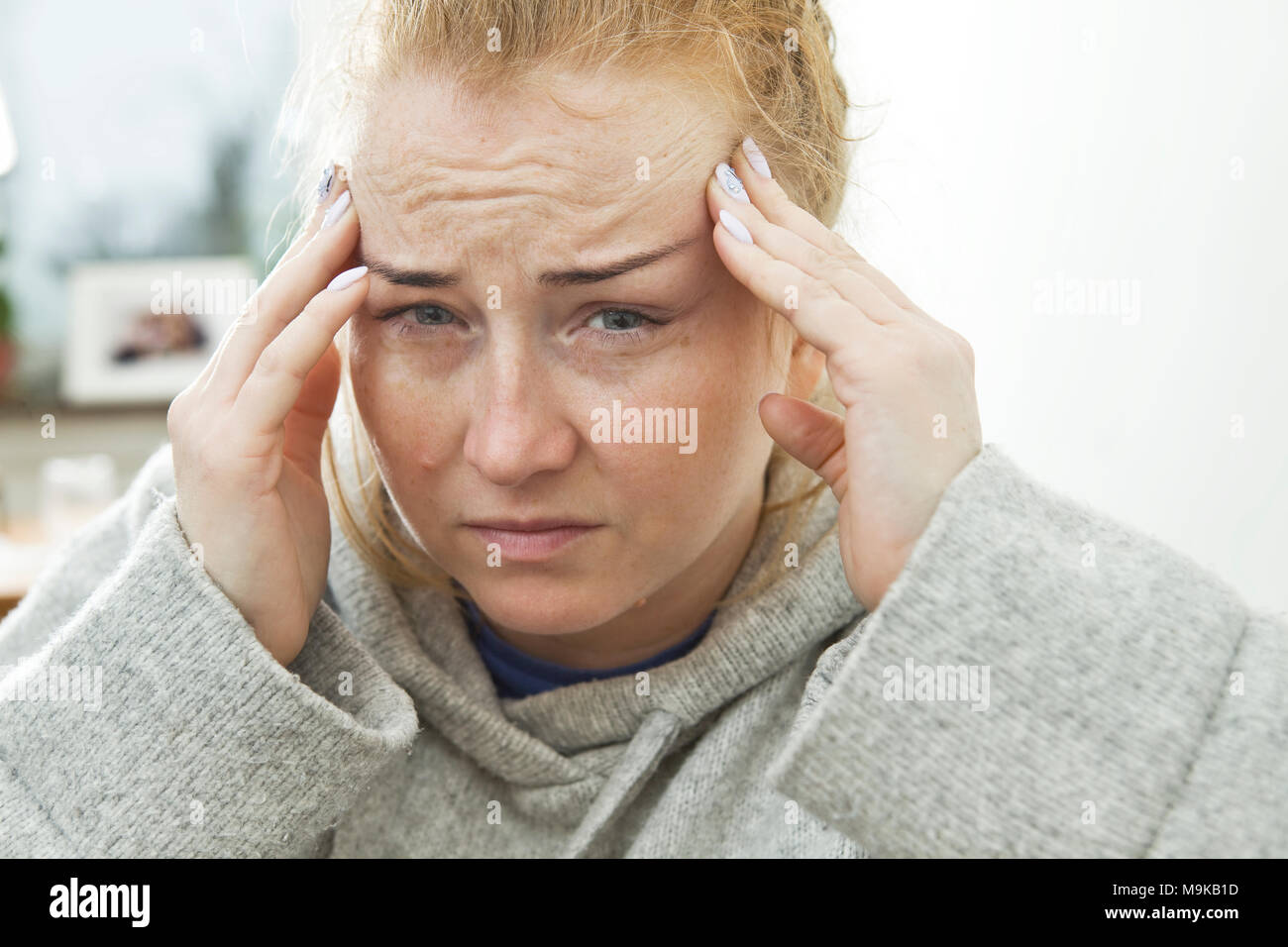Girl suffers from terrible headaches and compresses the head with fingers Stock Photo