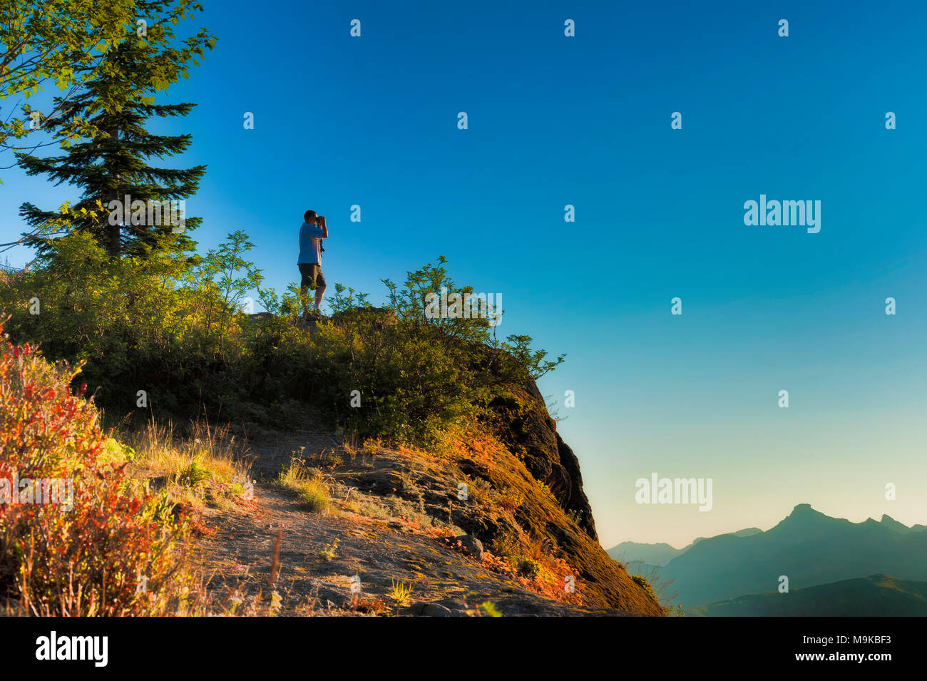 A Hiker Stands On A Ridge In The Early Morning Light To Get A