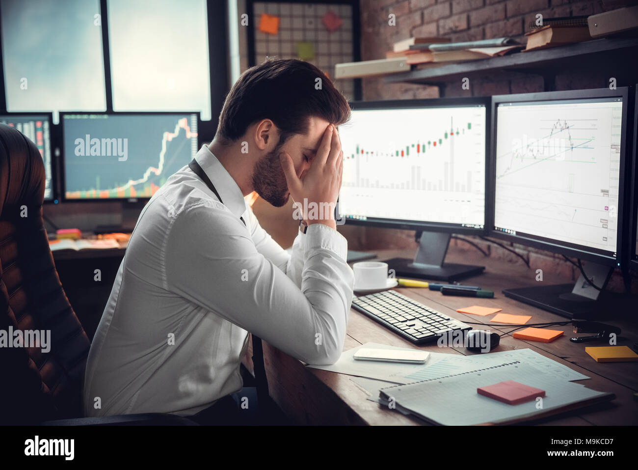 Frustrated depressed trader stressed by stock exchange fall on computer online graphs, sad ...