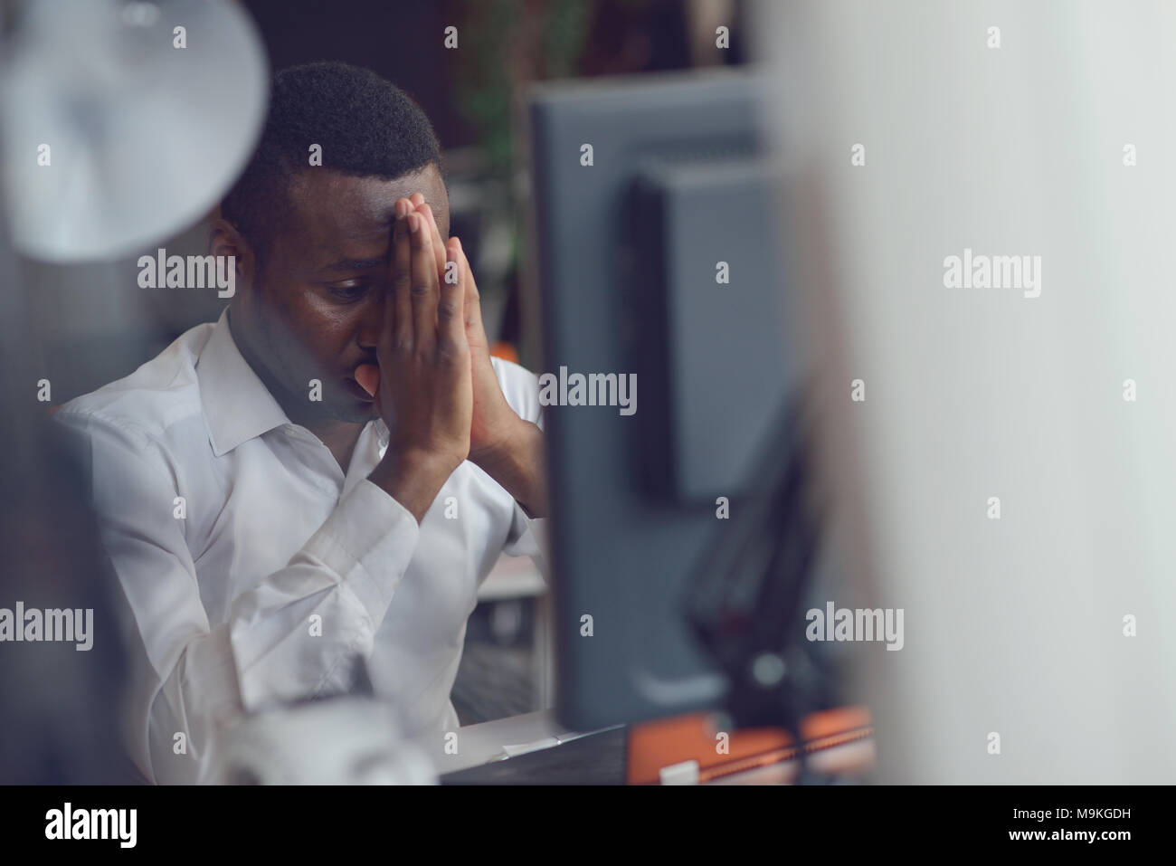 Stressed tired freelancer is having headache and thinking how to finish his work. Stock Photo