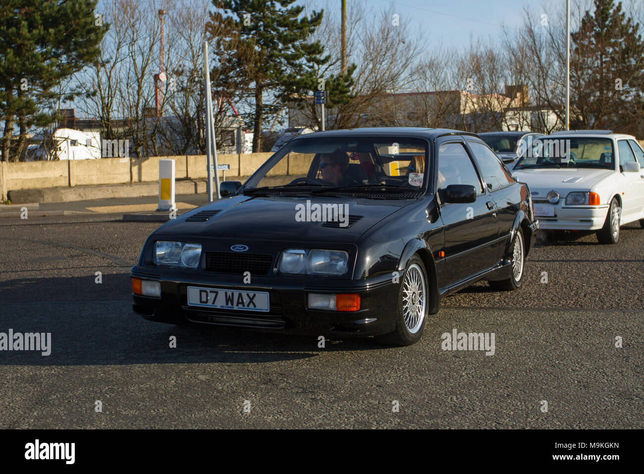 1986 black Ford Sierra Rs Cosworth petrol hatchback at the North-West Supercar event as cars and tourists arrive in the coastal resort. 1980s SuperCars are bumper to bumper on the seafront esplanade as classic & sports car enthusiasts enjoy a motoring day out. Stock Photo