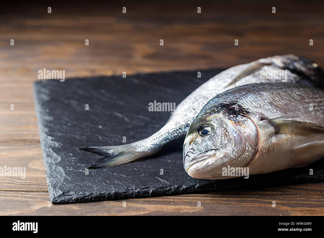 Fresh uncooked dorado or sea bream fish with lemon slices, spices and herbs. Mediterranean cuisine. Top view Stock Photo